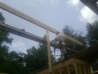 Carpenter setting a ridge beam over a new addition frame — Ice Dam Removal by Roofing Brothers in Brightwood